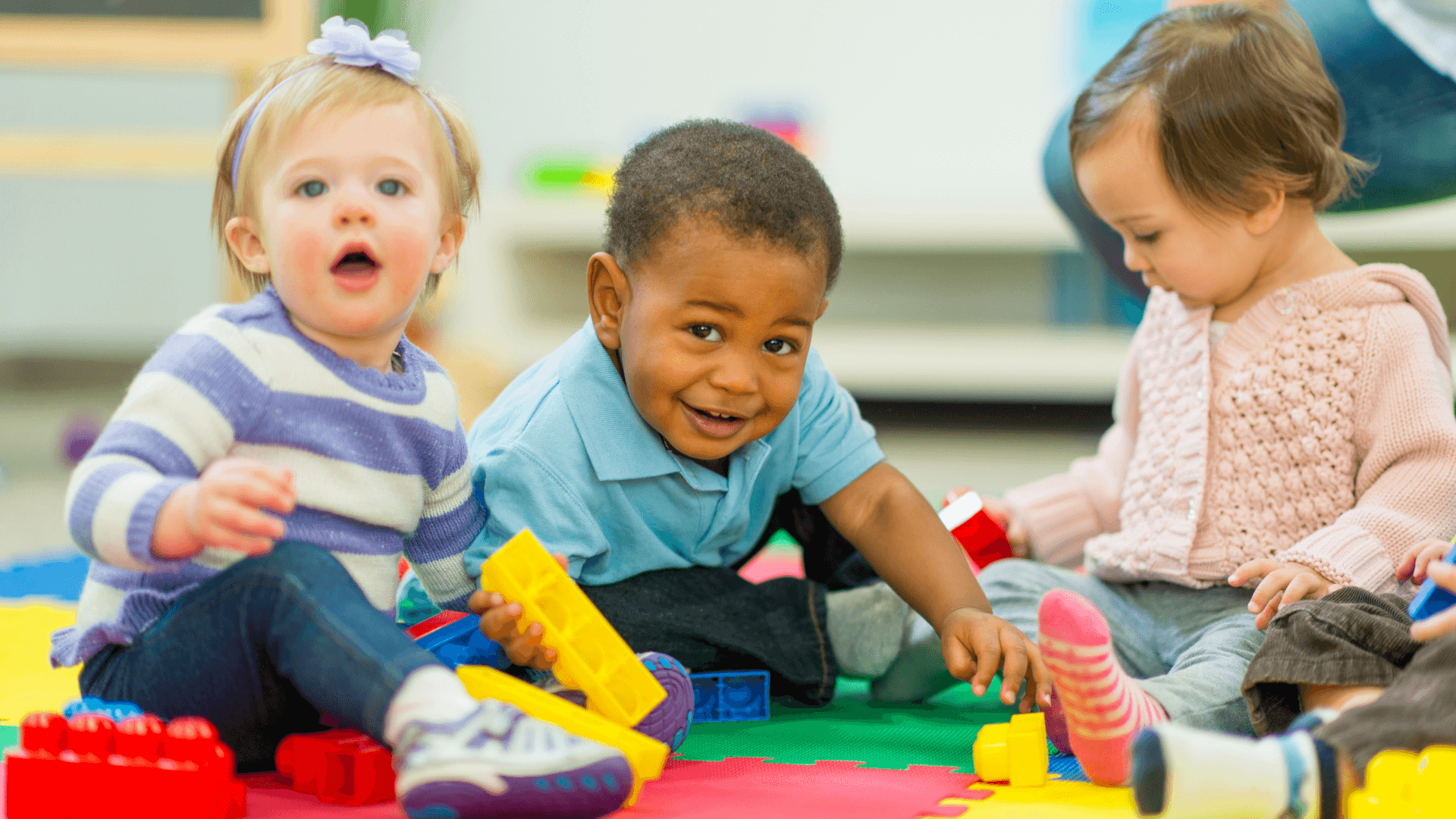 Three toddlers playing with blocks.