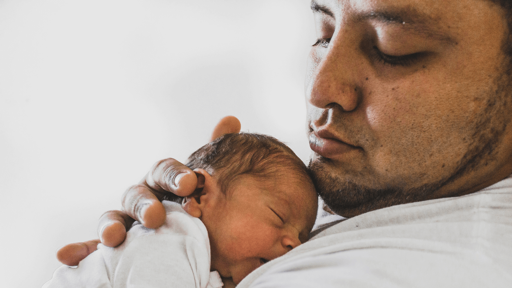 Father holding sleeping newborn baby