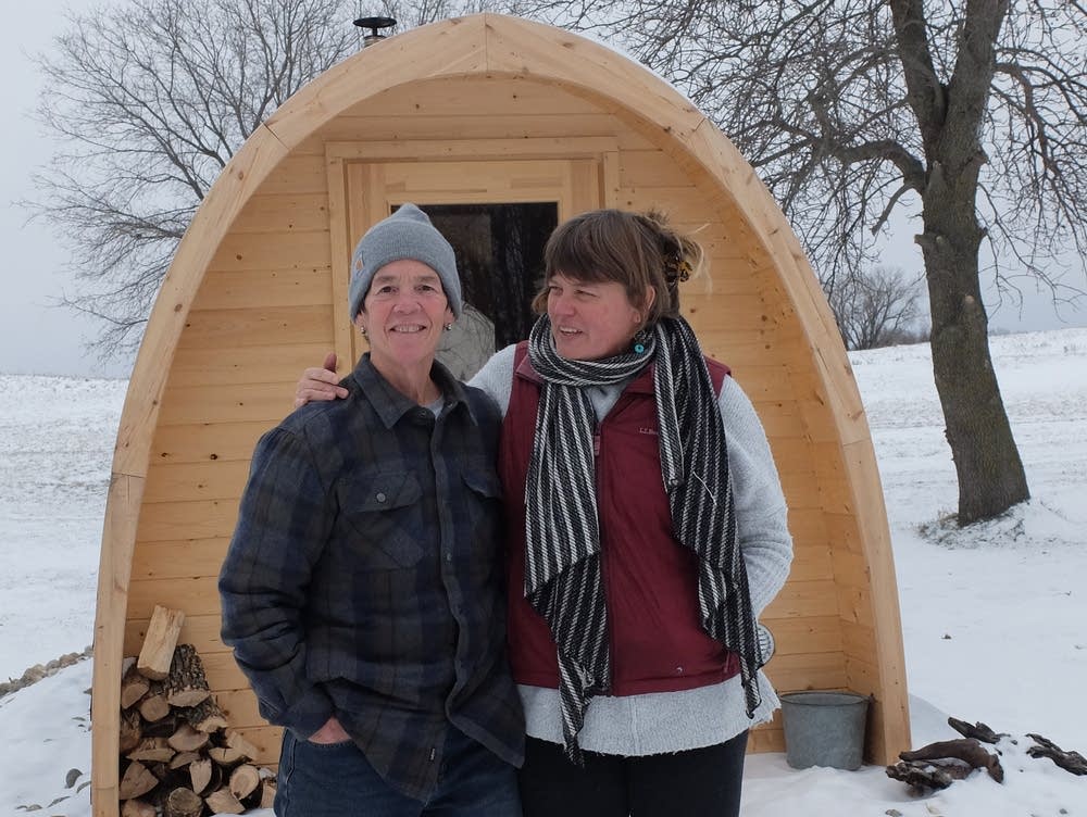 Kate and Amy stand in front of there sauna on a snowy winter day.