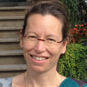 Adrianne is smiling and wearing glasses.