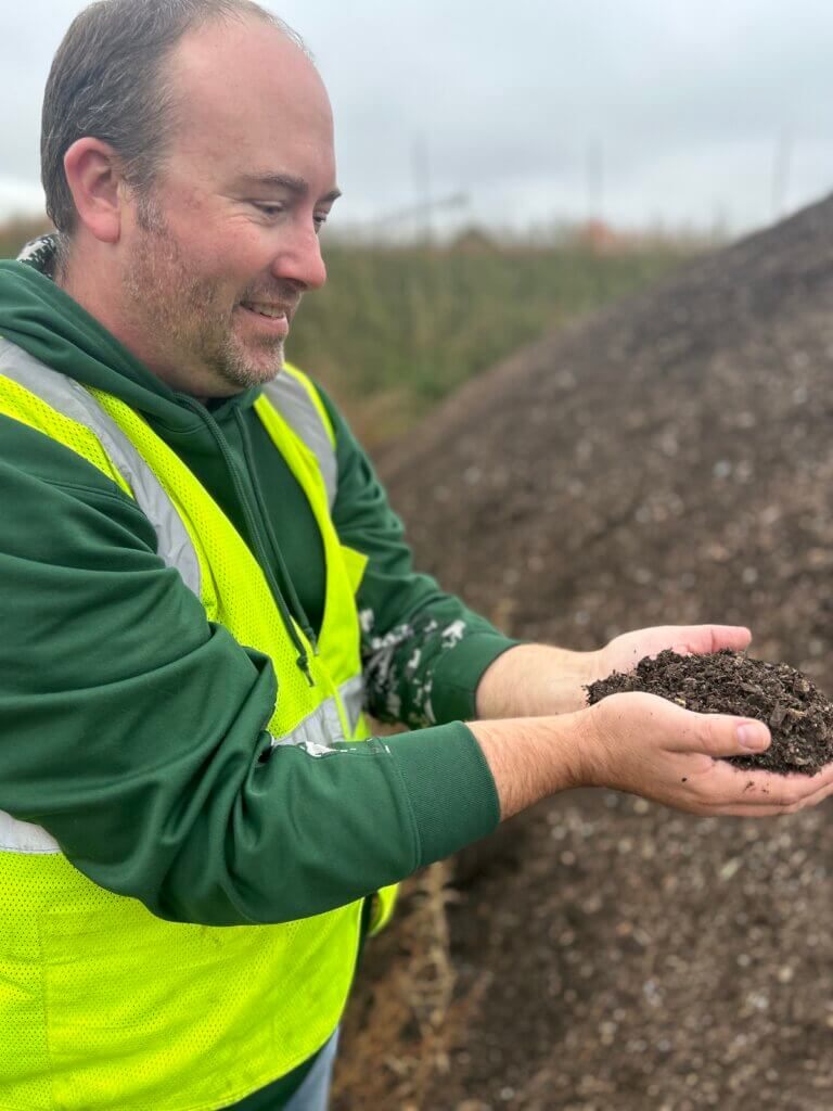 Nathan Reinbold holding a pile of finished compost