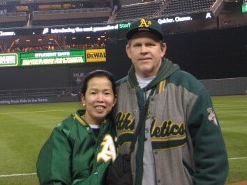 Owner of Heavenly Haven, Hannah Middleton, and Duane middleton stand next to each other smiling in the middle of a baseball field.