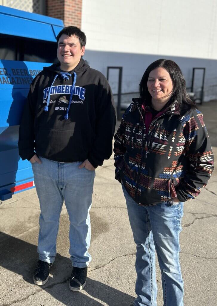 Amy Moore and Chris McDougall smiling in front of a recycling trailer