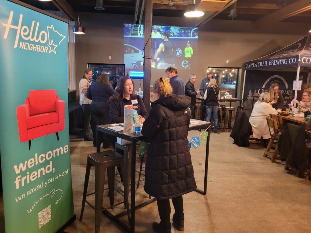 Hello Neighbor event at Copper Trail Brewing. A woman is standing at a table with another woman.