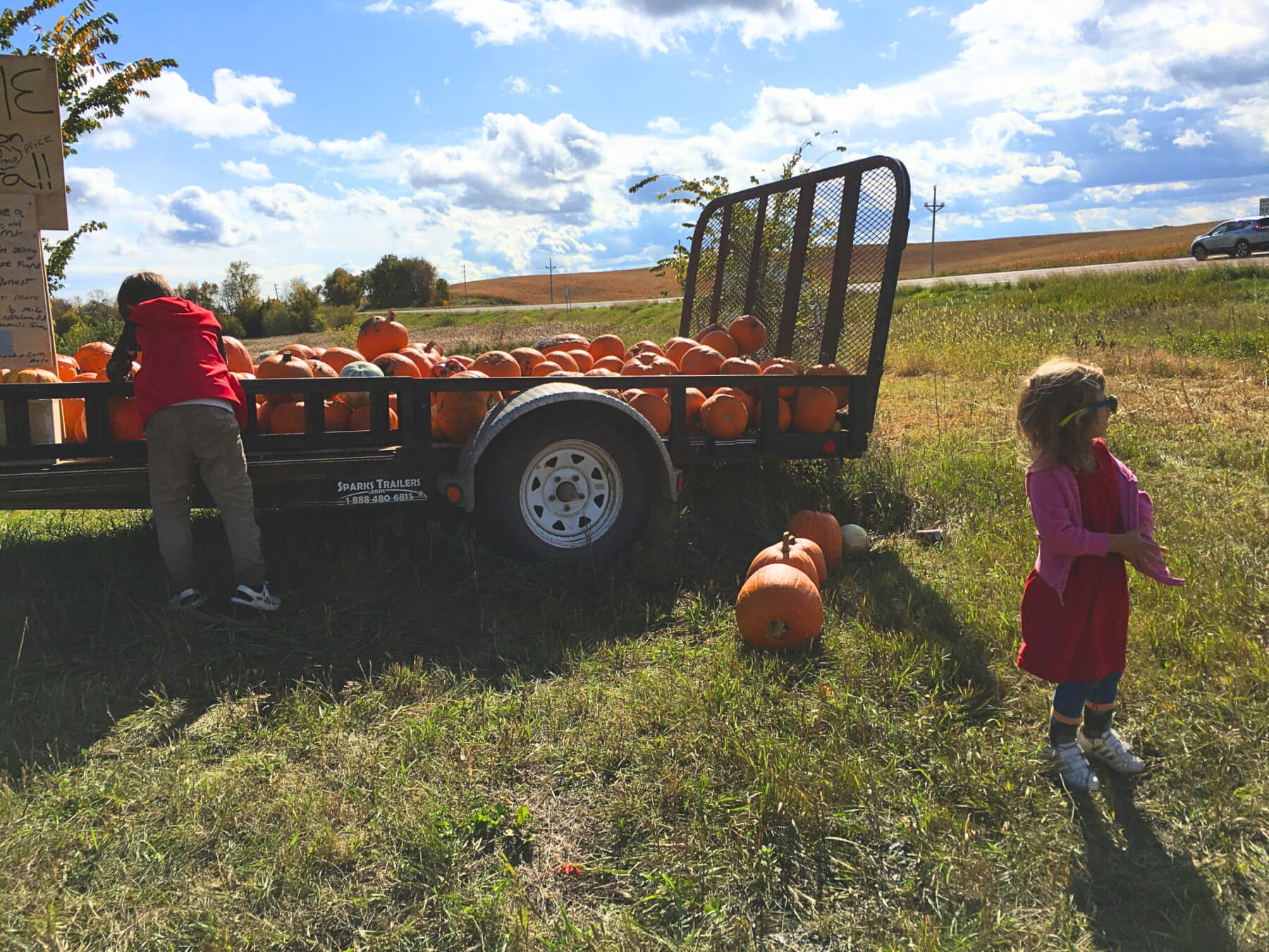 Children by a trailer with pumpkins in it