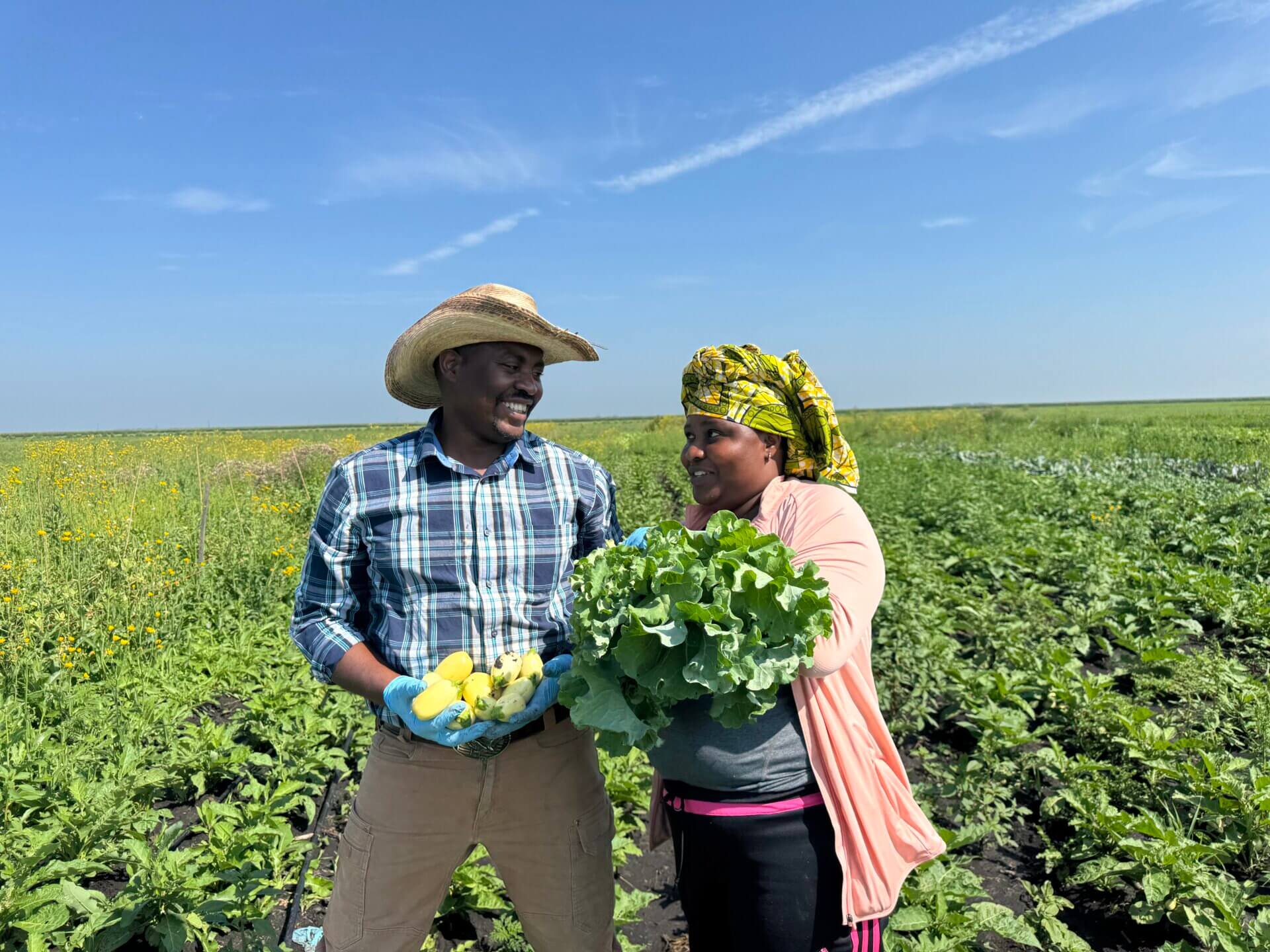 Caliton and Honoree on the farm holding vegetables.