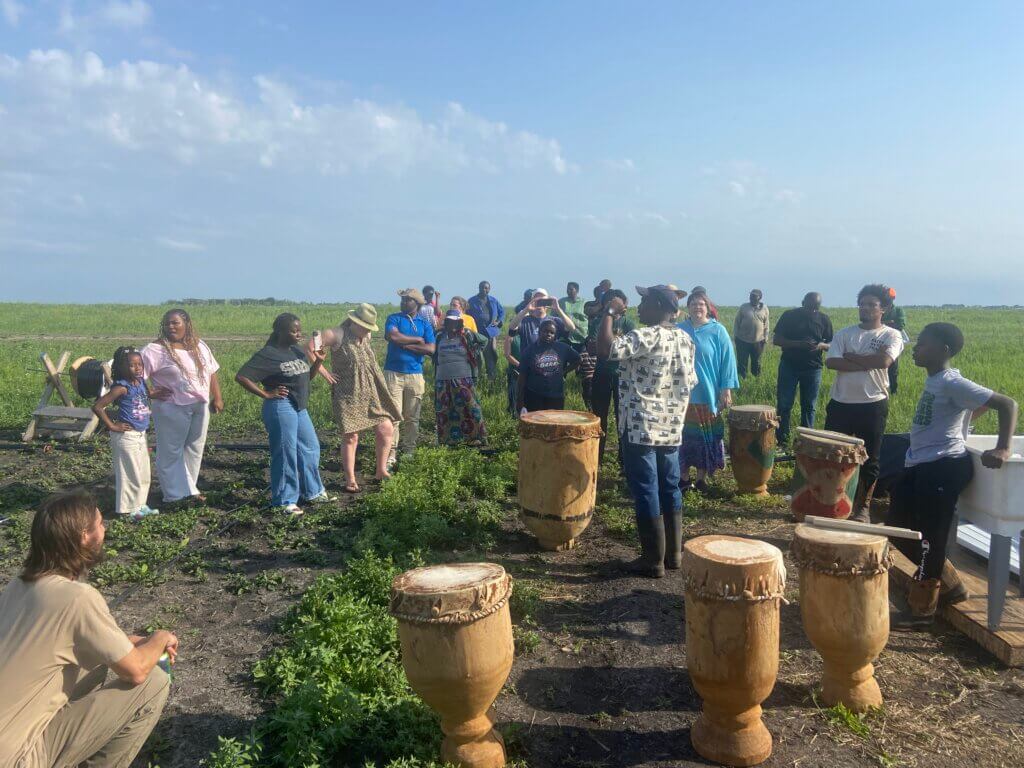 Farm event at New Roots. Caliton explains drumming.